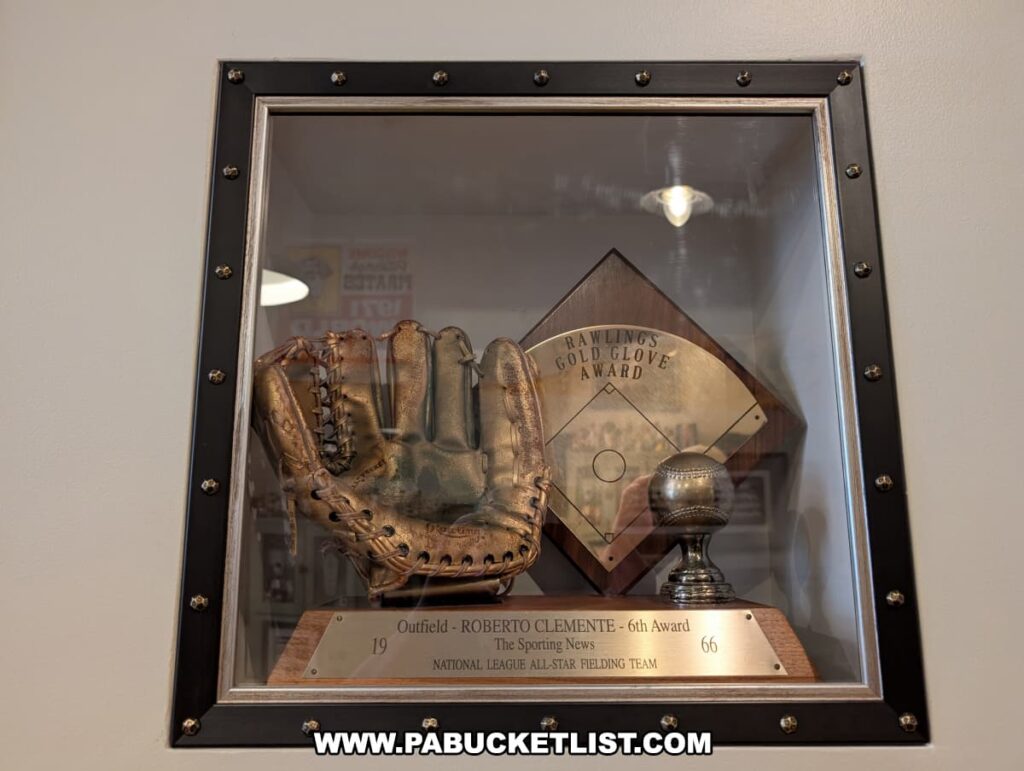 Display case at the Roberto Clemente Museum in Pittsburgh, PA, featuring Roberto Clemente’s 1966 Rawlings Gold Glove Award, including a well-worn leather glove, a golden baseball trophy, and an engraved plaque recognizing his sixth award for excellence as an outfielder on the National League All-Star Fielding Team.