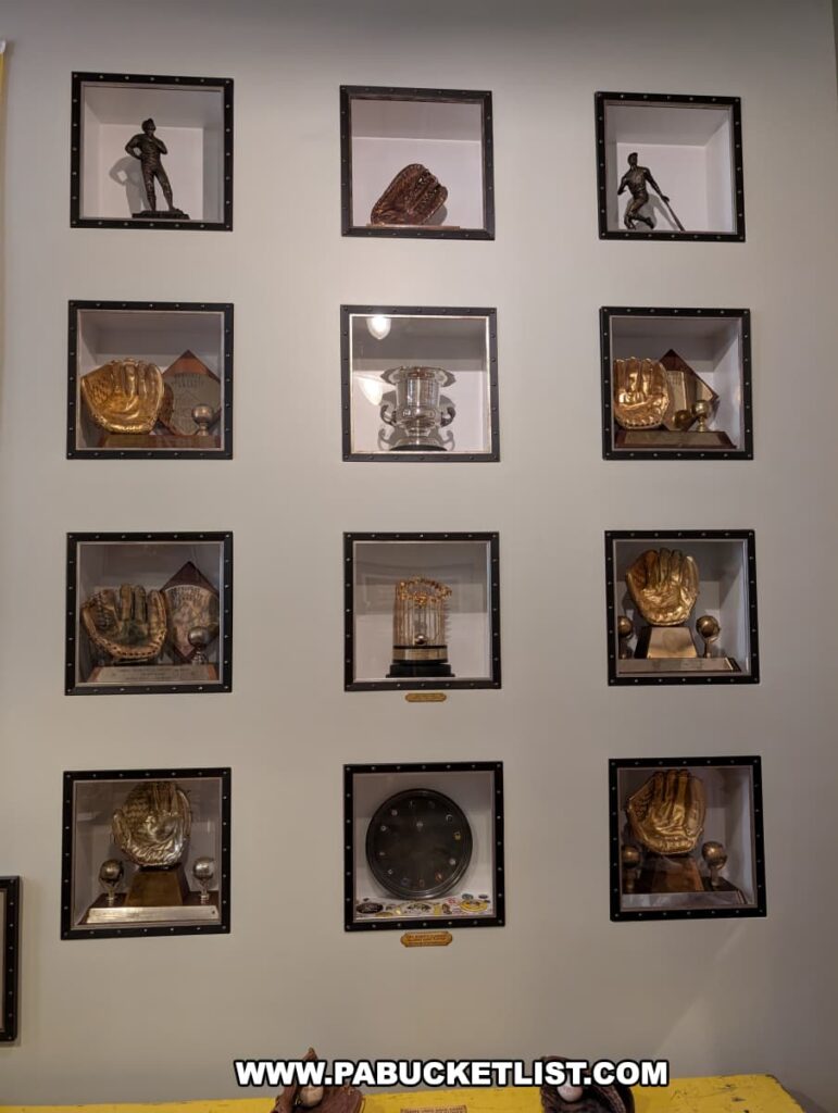 Wall display at the Roberto Clemente Museum in Pittsburgh, PA, featuring a collection of Roberto Clemente’s Gold Glove Awards and other baseball trophies, including golden baseball gloves, statues, and championship memorabilia, all arranged in individual shadowbox-style cases to honor his defensive excellence and career achievements.
