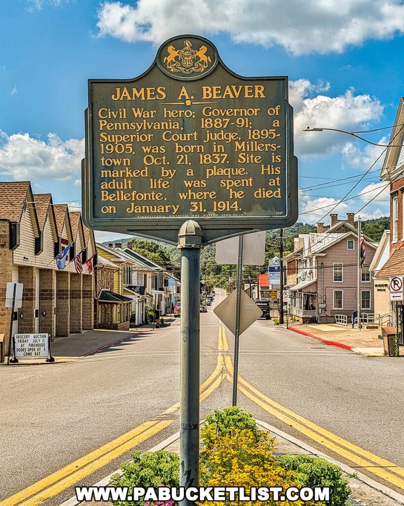 James A. Beaver historical marker in the center of Millerstown, Perry County, Pennsylvania, with American flags, small-town storefronts, and a blue sky with scattered clouds in the background.