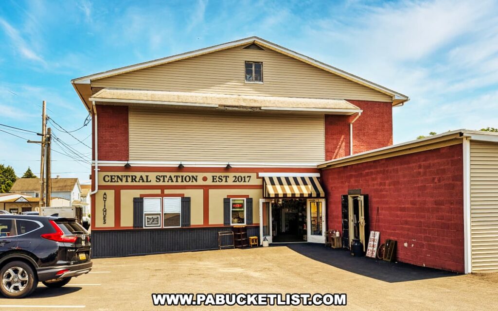 Exterior view of Central Station Antiques in Scranton, PA showing the two-story building with a tan and red facade, striped awning entrance, and parking area in front.