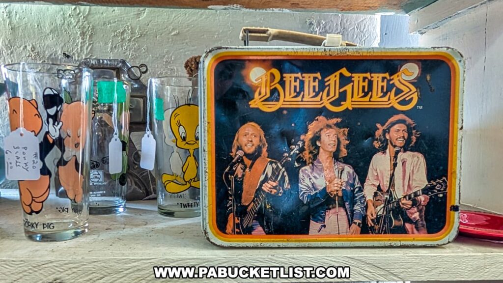 Close-up display at Central Station Antiques in Scranton, PA featuring a vintage Bee Gees lunchbox alongside collectible Looney Tunes character glasses with Porky Pig and Tweety Bird designs.
