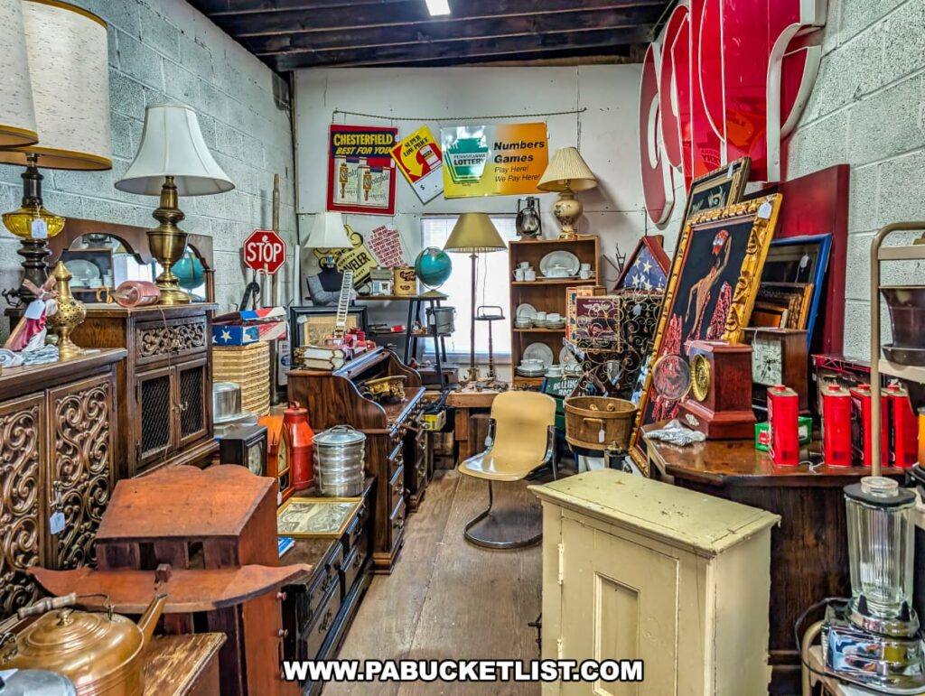Eclectic booth at Central Station Antiques in Scranton, PA filled with vintage furniture, table lamps, advertising signs, globes, framed artwork, kitchenware, and decorative collectibles arranged in a cozy display.