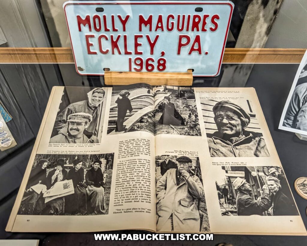 Exhibit at Eckley Miners’ Village in Luzerne County, Pennsylvania, featuring a 1968 license plate marked “Molly Maguires, Eckley, PA” and an open magazine with behind-the-scenes photos from the filming of the movie *The Molly Maguires*, highlighting the site’s role as the primary filming location.