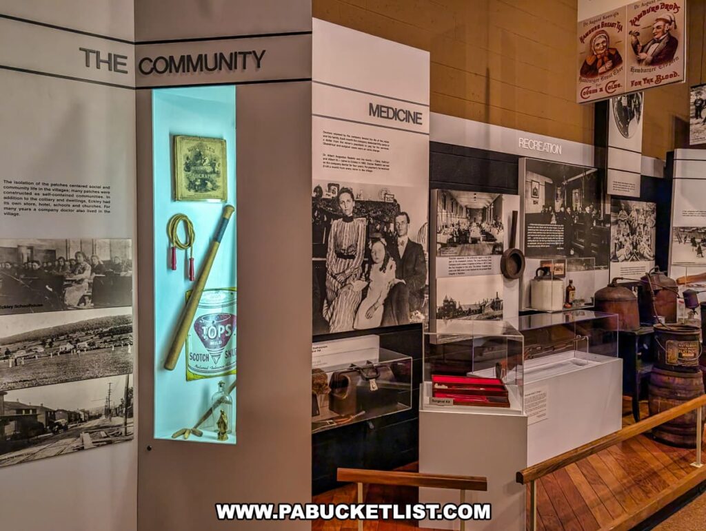Museum exhibit at Eckley Miners’ Village in Luzerne County, Pennsylvania, displaying artifacts, photos, and interpretive panels about community life, medicine, and recreation in the 19th-century coal mining patch town, including a doctor’s kit, tobacco tin, and vintage household items.