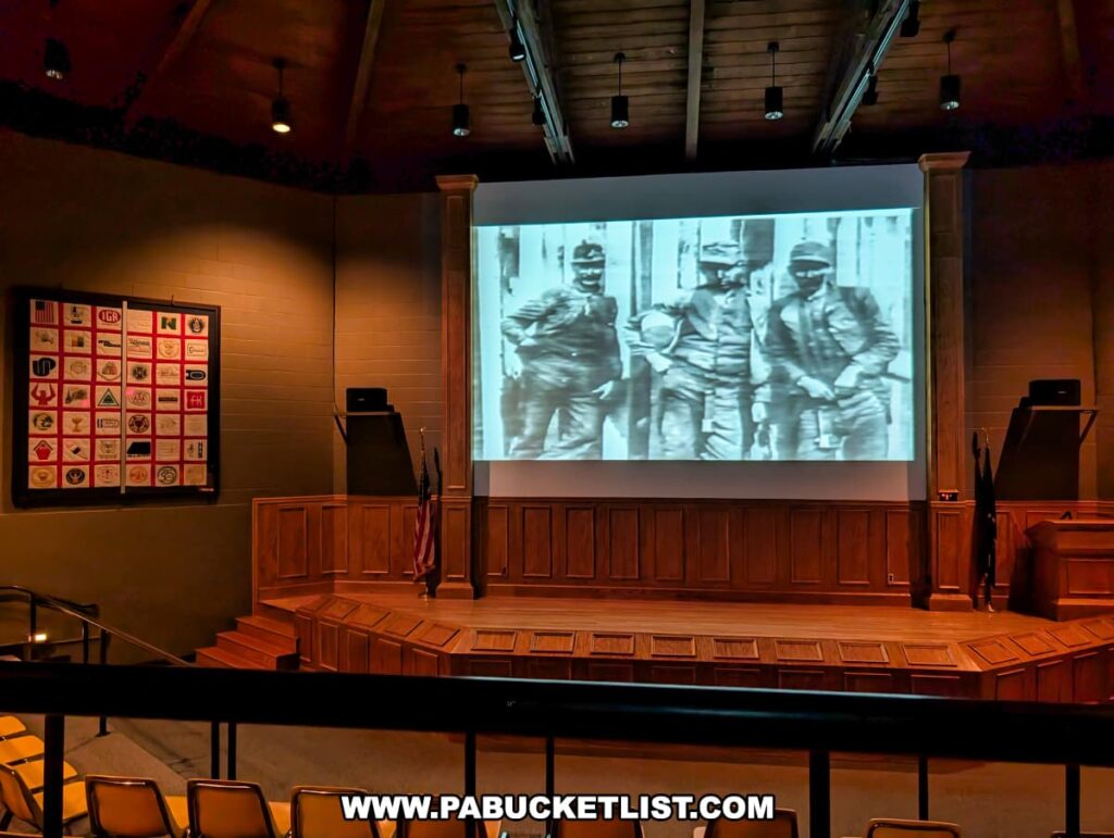 Museum theater at Eckley Miners’ Village in Luzerne County, Pennsylvania, showing a historic film about coal miners, with wooden stage paneling, flags, and seating for visitors as part of the educational experience at the preserved 19th-century coal mining patch town.