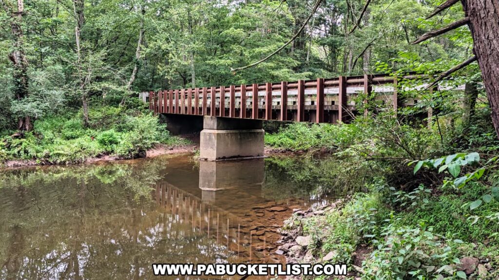 Wooden bridge spanning Nescopeck Creek at Nescopeck State Park, surrounded by lush green forest and reflected in the calm creek water.
