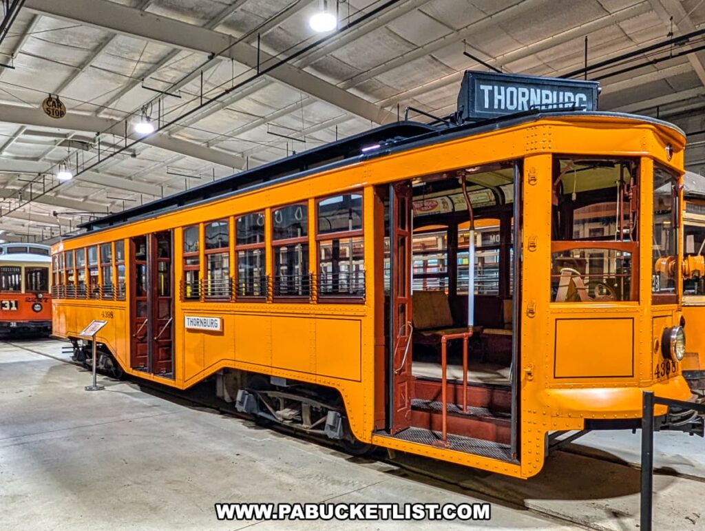 Bright orange vintage trolley with Thornburg route sign on display inside the Trolley Display Building at the Pennsylvania Trolley Museum in Washington County, Pennsylvania.