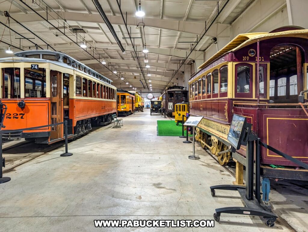 Rows of restored vintage trolleys in various colors and styles on display inside the Trolley Display Building at the Pennsylvania Trolley Museum in Washington County, Pennsylvania.