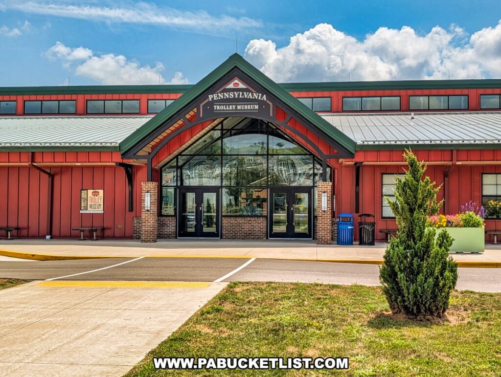Front entrance of the Pennsylvania Trolley Museum in Washington County, Pennsylvania, featuring a red and green building with a peaked roof, large glass doors, and welcoming signage above the entryway.