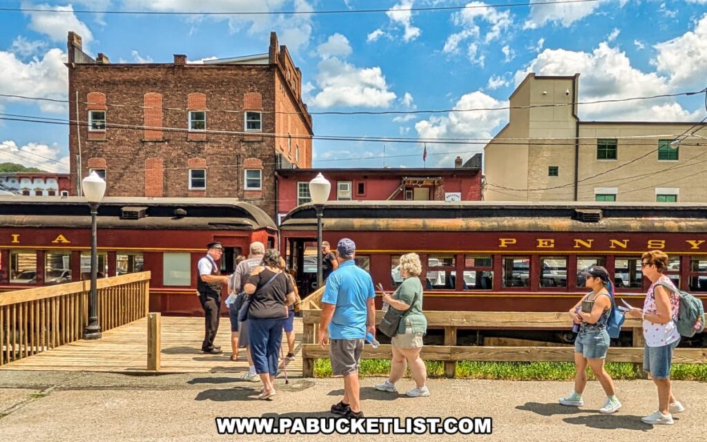 Passengers board a vintage maroon and gold Stourbridge Line excursion train in Honesdale, Wayne County, Pennsylvania, with historic brick buildings and a bright blue sky forming the backdrop.