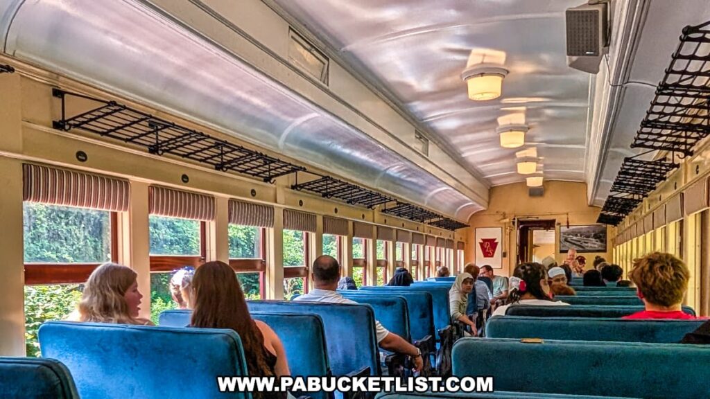 Passengers relax and enjoy the scenic ride aboard a vintage Stourbridge Line railcar with blue cushioned seats, large windows, and overhead luggage racks during a sightseeing excursion in Honesdale, Wayne County, Pennsylvania.