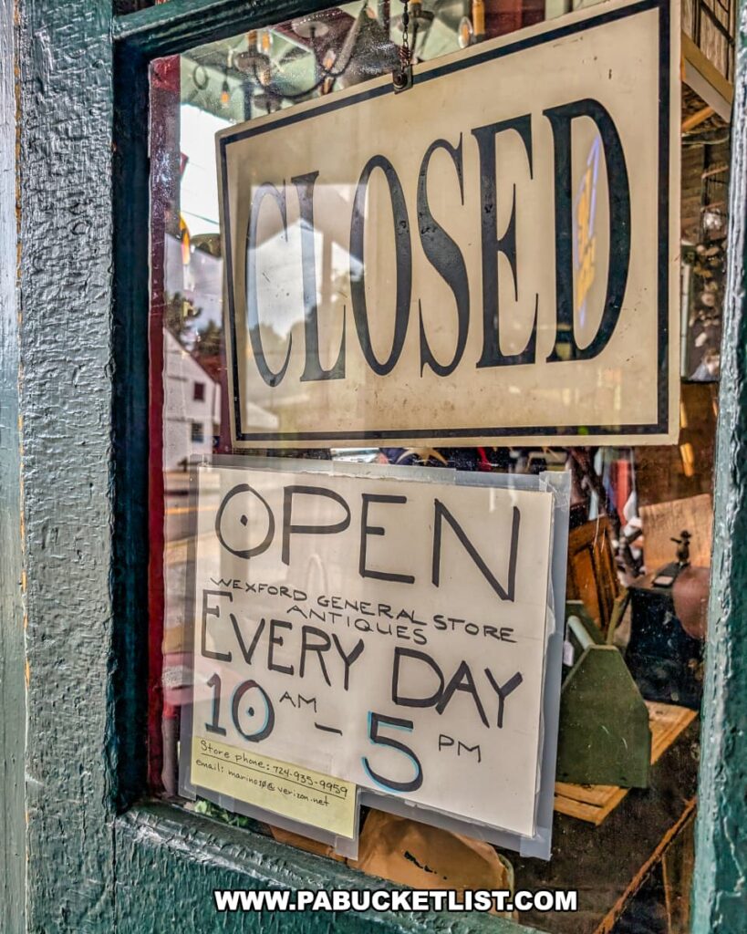 Handwritten sign on the entrance door of Wexford General Store Antiques in Allegheny County, PA showing store hours as open daily from 10 AM to 5 PM, with a larger “CLOSED” sign hanging above it.