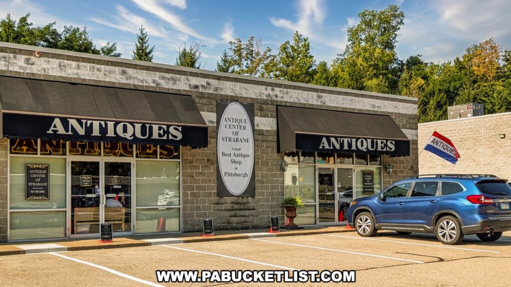 Exterior view of the Antique Center of Strabane in Canonsburg, Pennsylvania, showing the storefront with black awnings labeled “Antiques,” a large sign reading “Voted Best Antique Shop in Pittsburgh,” and a parking lot with a car in front.