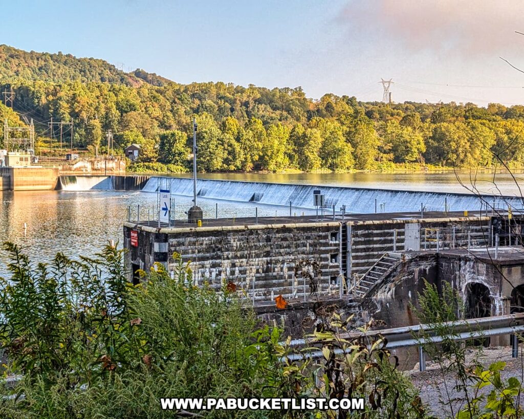 View of Lock and Dam Number 8 on the Allegheny River as seen from the Armstrong Trail in western Pennsylvania, with cascading water, historic stone lock walls, and forested hills in the background.