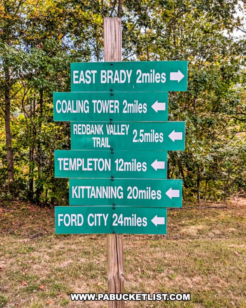 Directional signpost along the Armstrong Trail in western Pennsylvania showing distances to nearby points of interest, including East Brady (2 miles), Coaling Tower (2 miles), Redbank Valley Trail (2.5 miles), Templeton (12 miles), Kittanning (20 miles), and Ford City (24 miles).