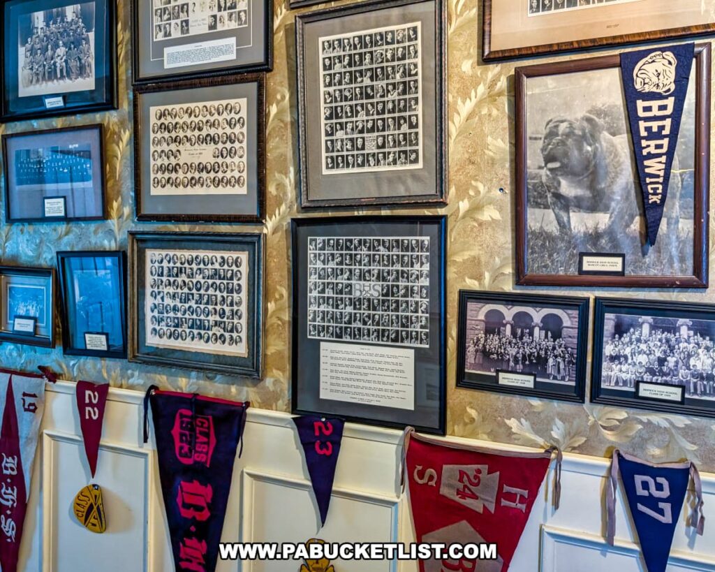 Historic Berwick school and sports memorabilia on display at the Berwick Historical Society Museum in Columbia County, PA, featuring framed class photos, vintage sports team portraits, and colorful felt school pennants from various graduating classes.