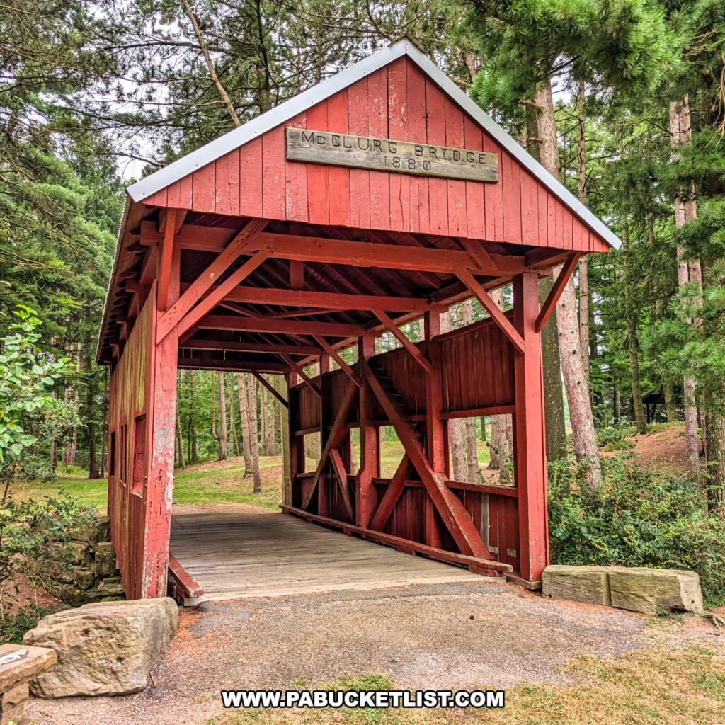 Front view of the McClurg Covered Bridge in Washington County, Pennsylvania, a small red wooden Kingpost truss bridge built in 1880 and now spanning a dry ravine in Hanover Township Park.