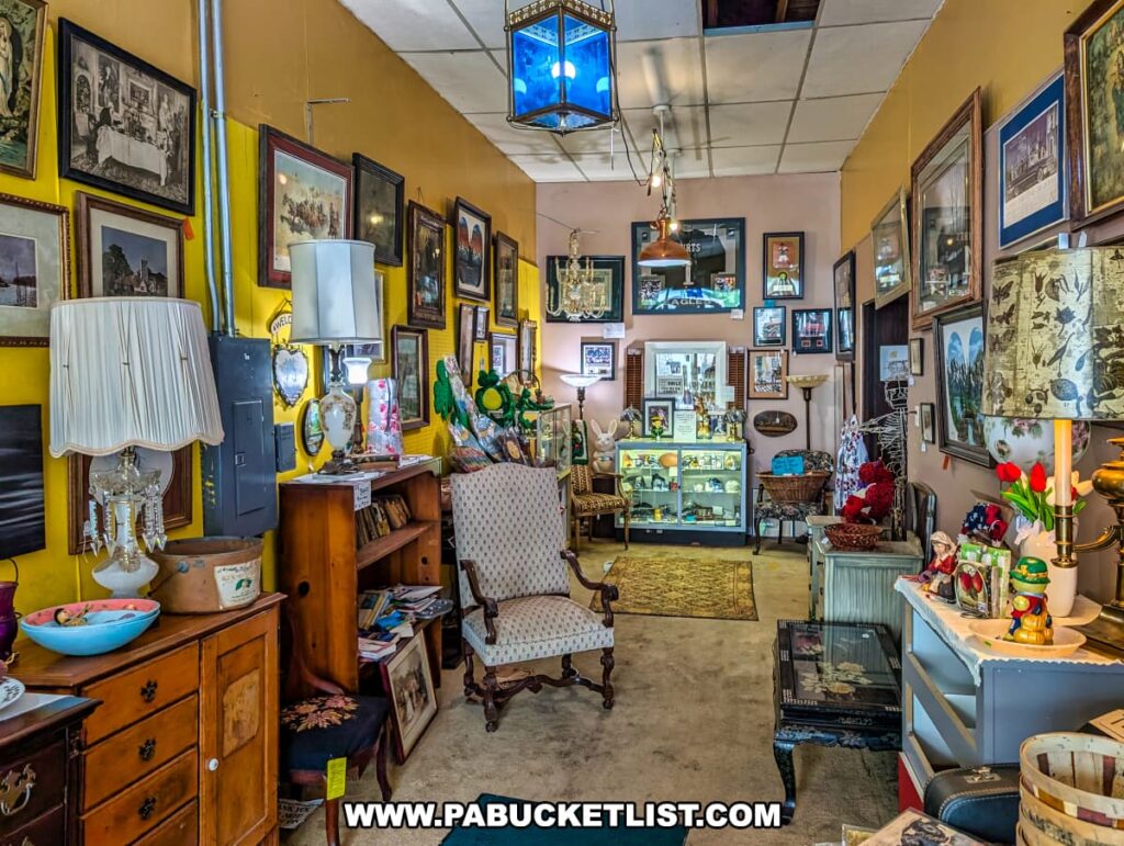 Cozy vendor booth at Plains Antiques in Luzerne County, PA, featuring vintage lamps, framed wall art, antique chairs, wooden furniture, and a display case filled with small collectibles in this two-level multi-vendor antique shop near Wilkes-Barre.