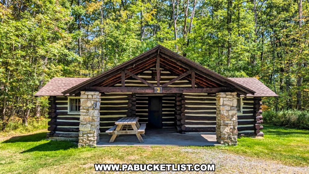 Rustic log rental cabin built by the Civilian Conservation Corps at SB Elliott State Park in Clearfield County, Pennsylvania, with stone pillars, a covered porch, and a picnic table set against a backdrop of dense green forest.