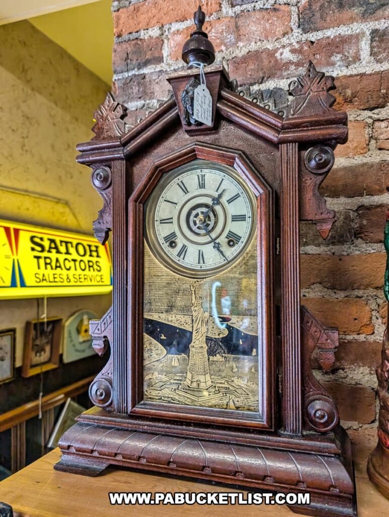 Close-up of a vintage wooden mantel clock with ornate carvings and Roman numerals, featuring an etched glass panel of the Statue of Liberty, displayed against an exposed brick wall at Vintage Secrets Antiques in Canonsburg, Washington County, PA.