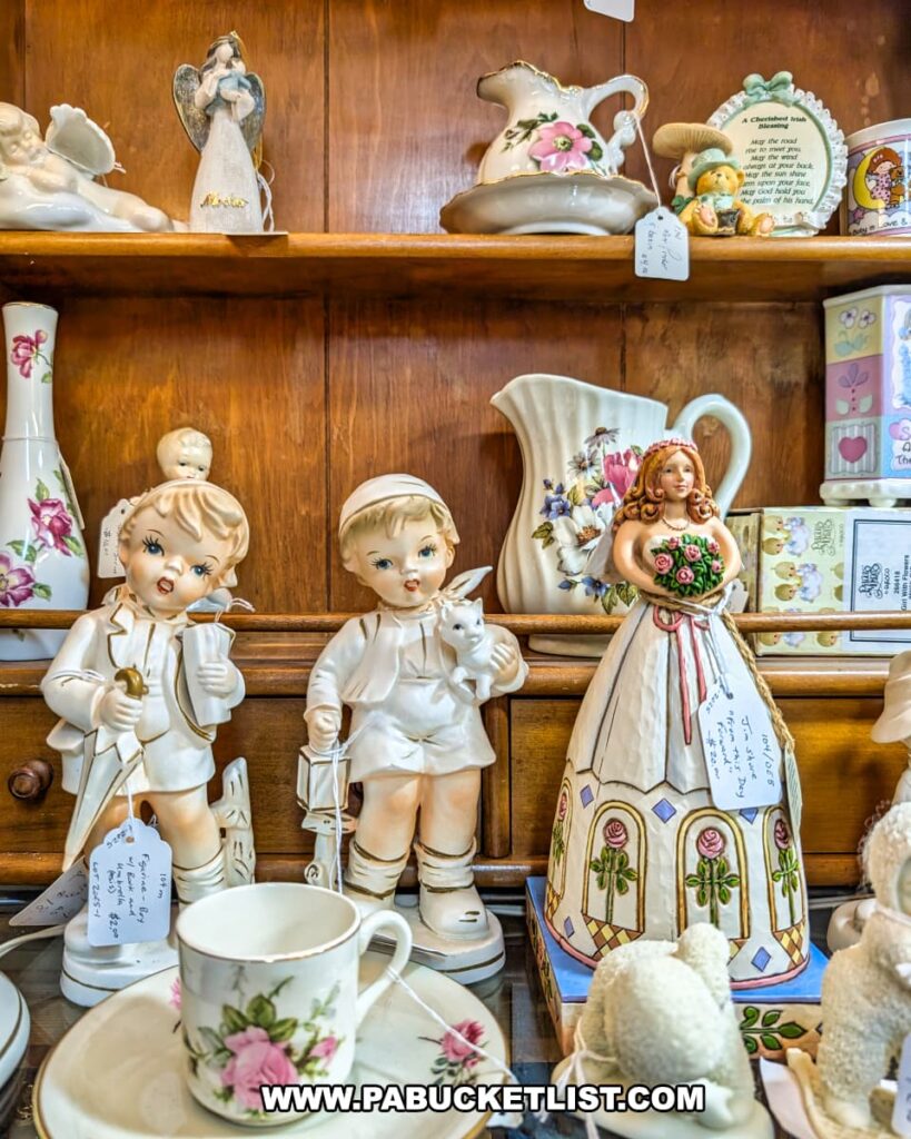 Display of delicate vintage figurines, floral-patterned pitchers, vases, and teacups on wooden shelves at Vintage Secrets Antiques in Canonsburg, Washington County, PA, showcasing the variety of collectibles available in the multi-vendor antique mall.
