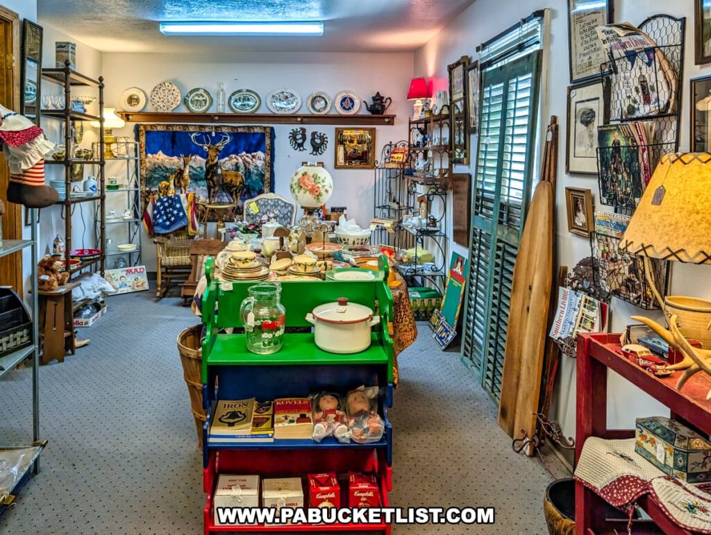 Vendor booth at Vintage Secrets Antiques in Canonsburg, Washington County, PA, displaying vintage cookware, glassware, decorative plates, lamps, framed art, and collectible items arranged on shelves and tables throughout the room.
