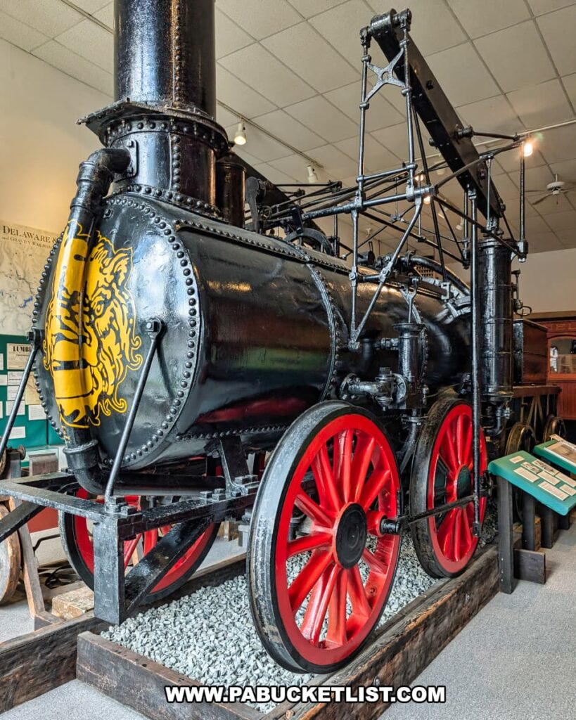 Full-size replica of the Stourbridge Lion locomotive on display at the Wayne County Historical Society Museum in Honesdale, Pennsylvania, featuring a black iron body with red wheels and a yellow lion emblem on the front boiler.