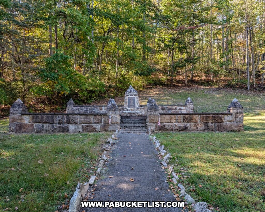 View of the Captain Phillips’ Rangers Memorial in Bedford County, Pennsylvania, showing the stone monument and surrounding low stone wall at the end of a tree-lined path on a peaceful forested hillside.