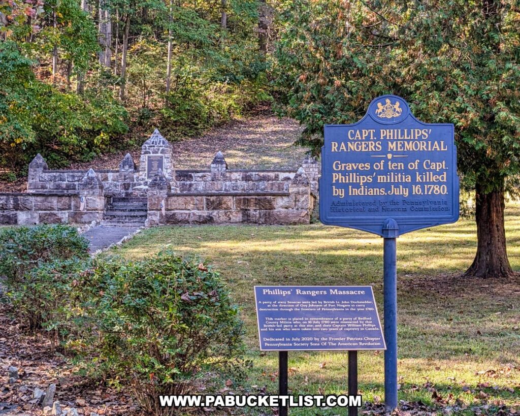 View of the Captain Phillips’ Rangers Memorial in Bedford County, Pennsylvania, featuring two historical markers in the foreground describing the 1780 massacre of Captain Phillips’ militia, with the stone monument and wooded hillside visible in the background.