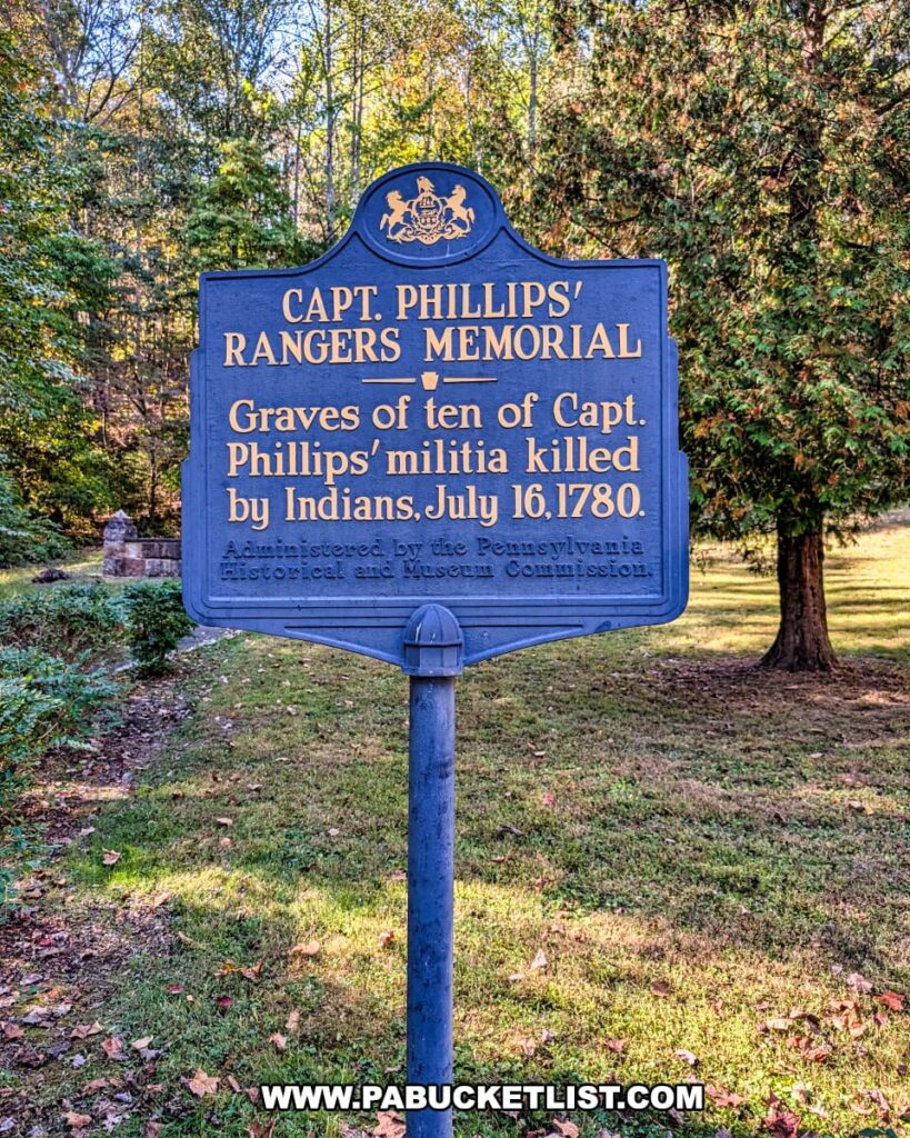 Close-up of the blue Pennsylvania Historical and Museum Commission marker for the Captain Phillips’ Rangers Memorial in Bedford County, Pennsylvania, commemorating the graves of ten militia members killed in the July 16, 1780 attack, with the wooded memorial grounds visible in the background.