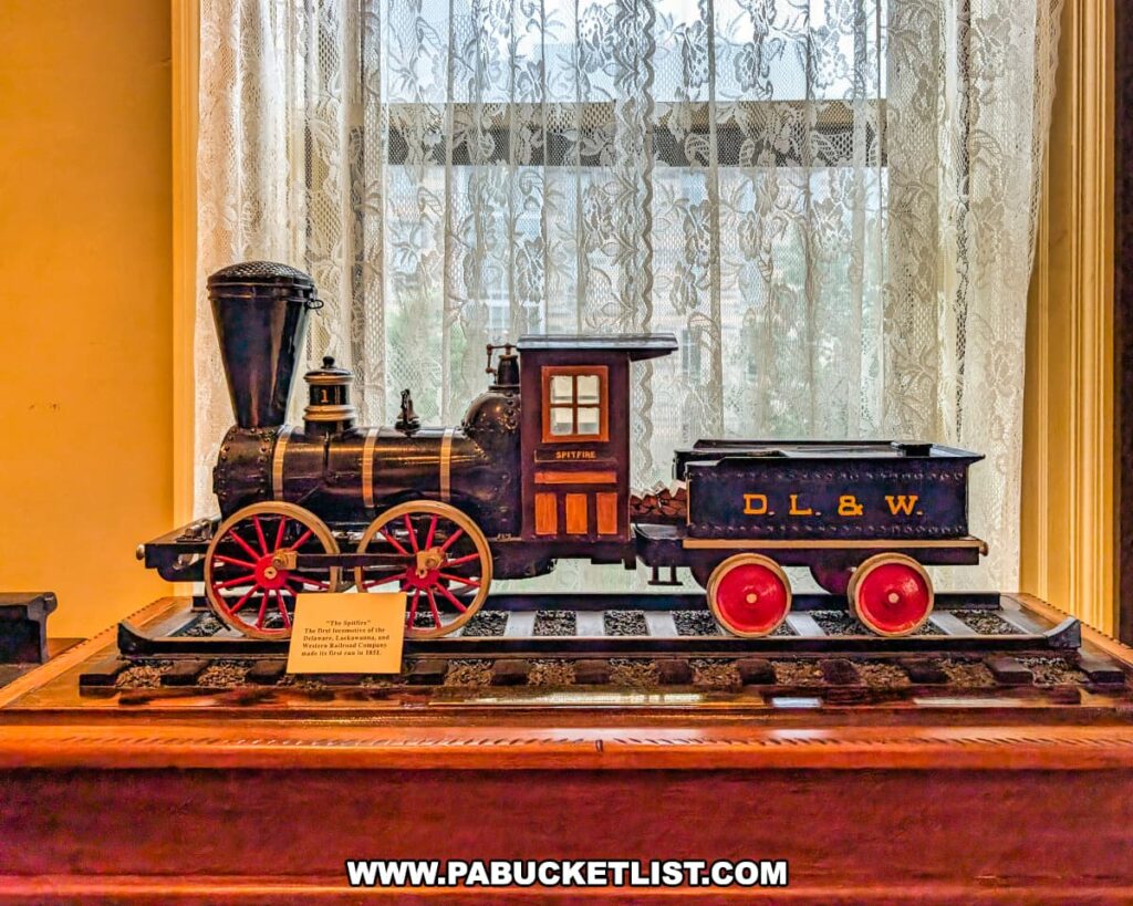 Display of a model locomotive labeled “D.L.&W. Spyfire” inside the Lackawanna Historical Society Museum in Scranton, Pennsylvania. The intricately detailed replica of the early Delaware, Lackawanna & Western Railroad engine sits on a wooden base in front of a lace-curtained window, illustrating the region’s deep connection to railroading and industrial history.