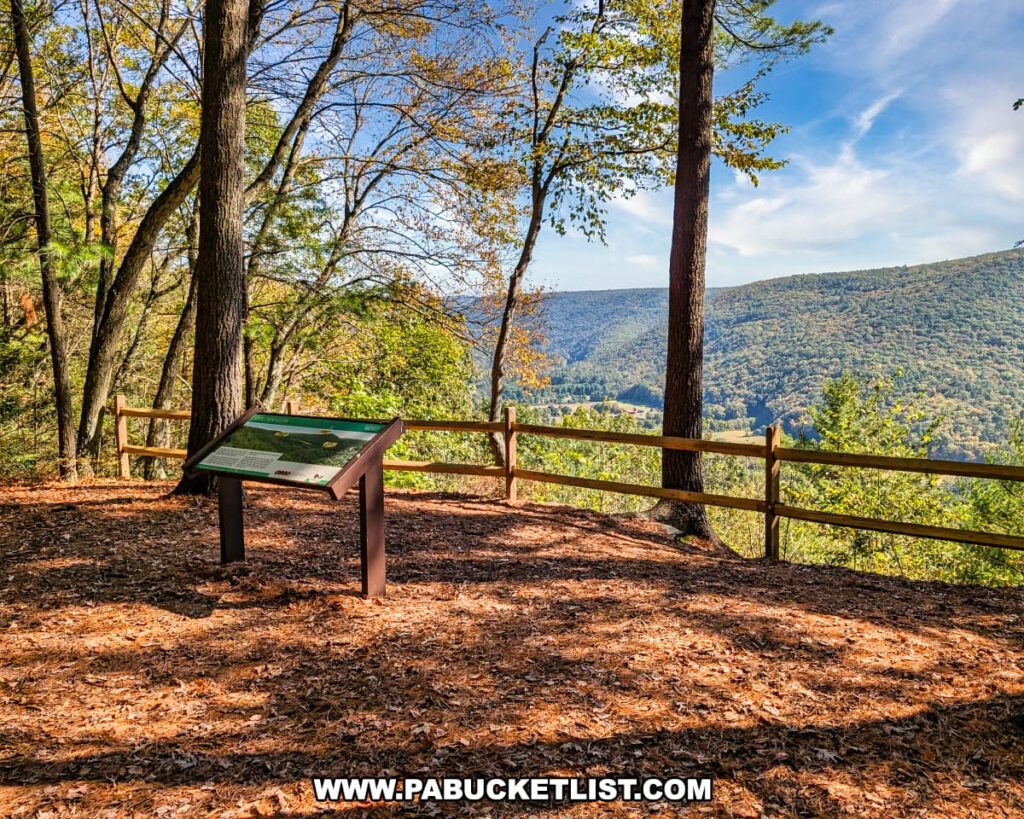 Scenic overlook at Doe Pen Vista in Rider Park, Lycoming County, Pennsylvania, featuring an informational sign, wooden fence, and sweeping views of forested mountains and valleys under a bright blue autumn sky.