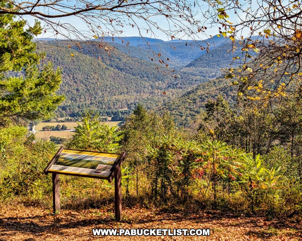 Informational sign at Katy Jane East Vista in Rider Park, Lycoming County, Pennsylvania, overlooking a valley framed by forested mountains and rolling hills under a clear blue sky.