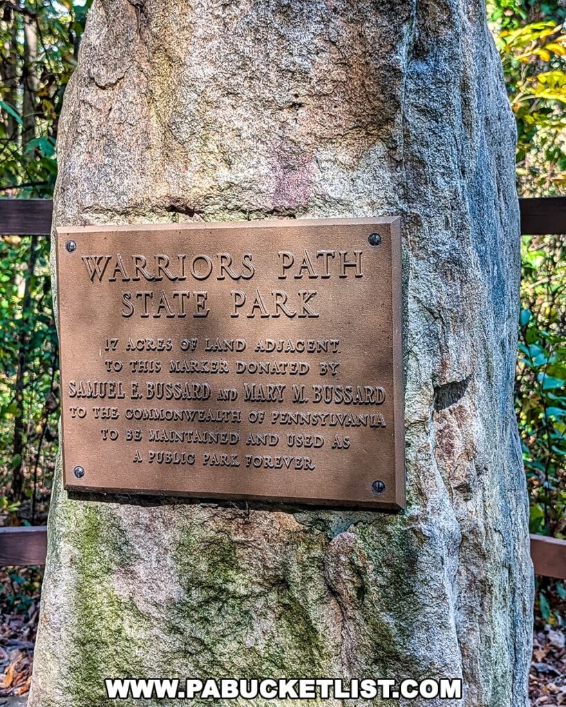 A bronze dedication plaque mounted on a large stone monument at Warriors Path State Park in Bedford County, Pennsylvania, commemorating the 17-acre land donation by Samuel E. and Mary M. Bussard that helped establish the park.