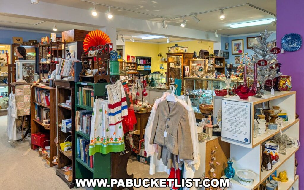 Bright, colorful aisle inside Apple Hill Antiques near State College, filled with vintage clothing, books, holiday décor, glassware, and collectibles arranged on shelves, racks, and display cases.