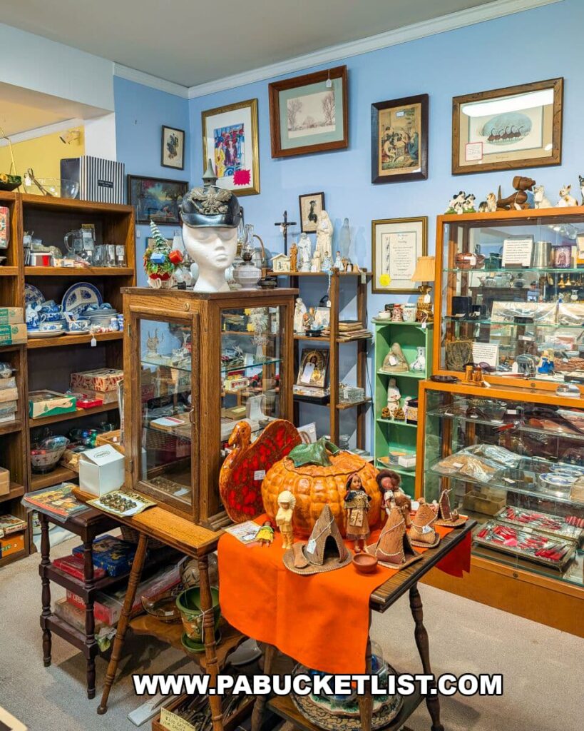 Colorful display of vintage holiday décor, figurines, framed artwork, and collectible items arranged on tables, shelves, and glass cases inside Apple Hill Antiques near State College.