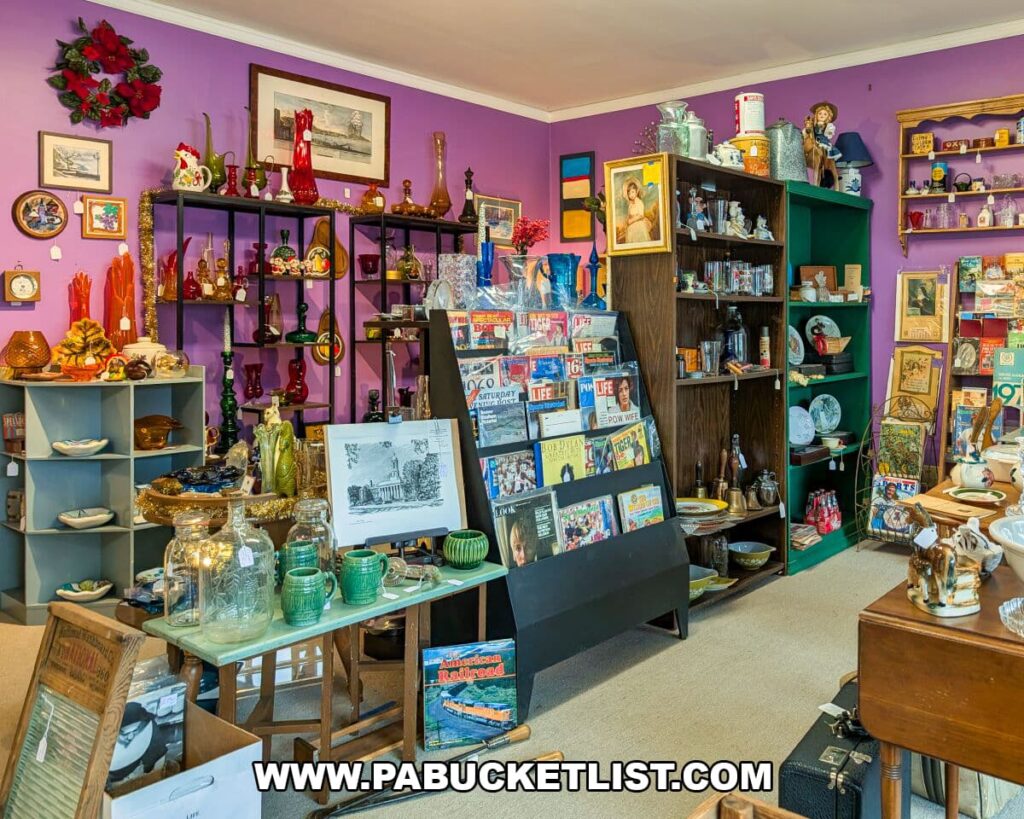 Vibrant room inside Apple Hill Antiques near State College showcasing colorful glassware, vintage magazines, artwork, pottery, and assorted collectibles displayed on shelves and tables.