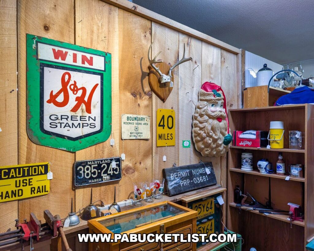 Wood-paneled wall at Apple Hill Antiques near State College decorated with vintage signs, old license plates, a Santa wall plaque, and mounted antlers, surrounded by shelves of retro tools and collectibles.