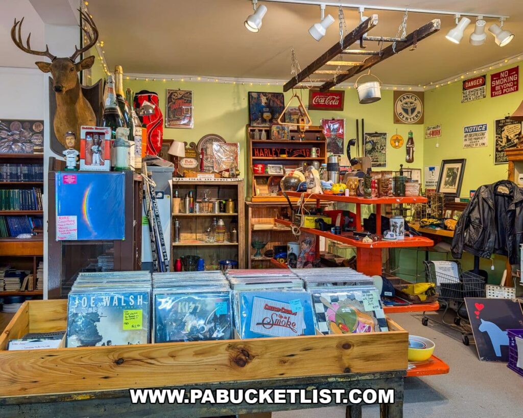 Eclectic corner of Apple Hill Antiques near State College featuring bins of vinyl records, a mounted deer head, vintage signs, Harley-Davidson memorabilia, retro tools, and assorted collectibles displayed on shelves and tables.