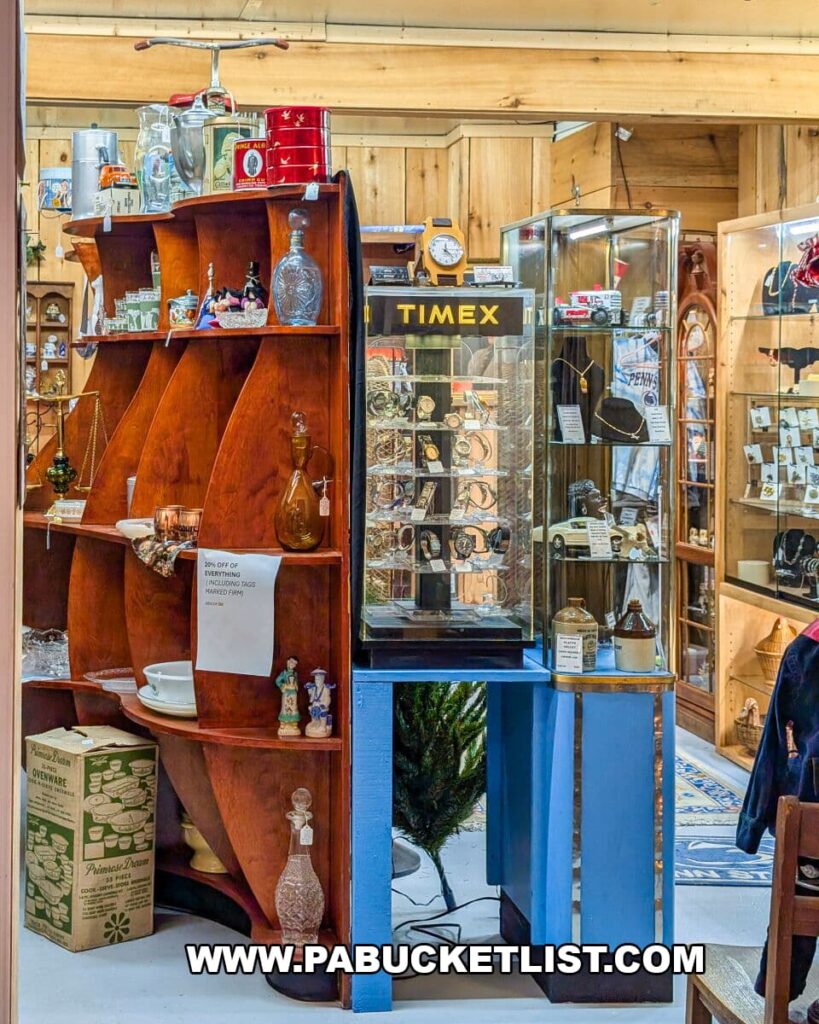 Display area at Apple Hill Antiques near State College featuring a vintage Timex watch case surrounded by shelves of glassware, figurines, pottery, and assorted antiques.