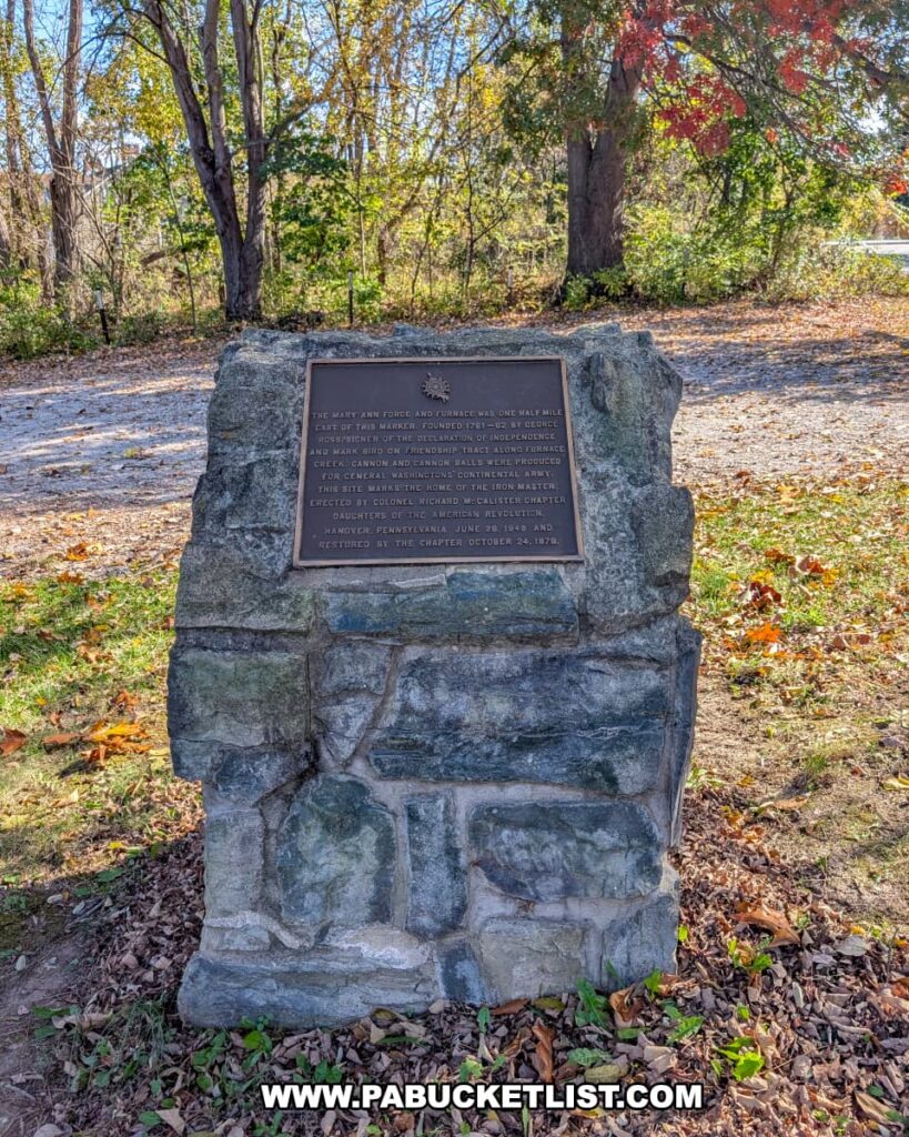 A stone monument with a bronze plaque honors the historic Mary Ann Furnace at Codorus State Park in York County, Pennsylvania, surrounded by autumn leaves and trees.