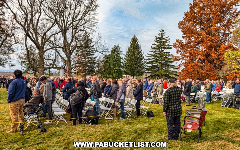 A large crowd gathers among the trees at Soldiers’ National Cemetery in Gettysburg, standing for the Dedication Day ceremony honoring Lincoln’s Gettysburg Address and the soldiers who fought there.