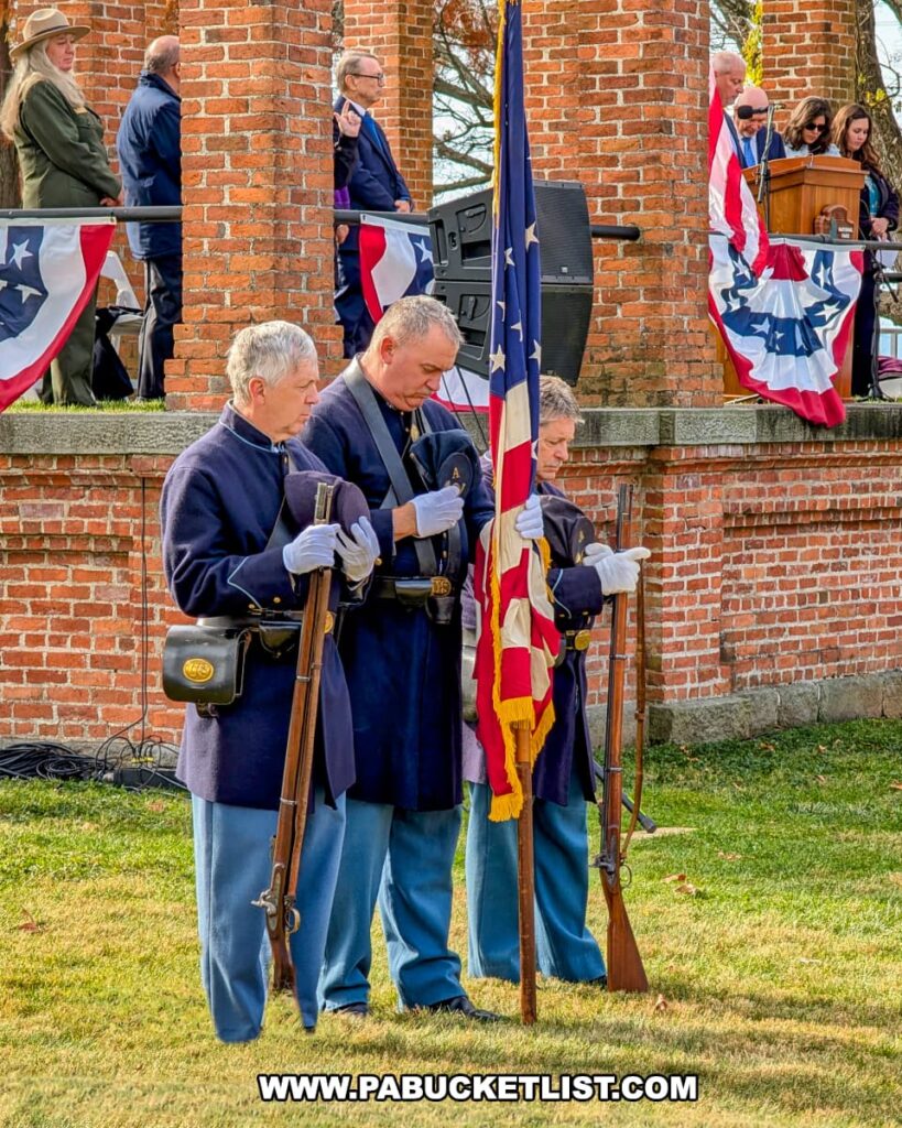Civil War reenactors dressed in Union uniforms bow their heads in prayer while holding rifles and an American flag during the Dedication Day ceremony at Soldiers’ National Cemetery in Gettysburg.