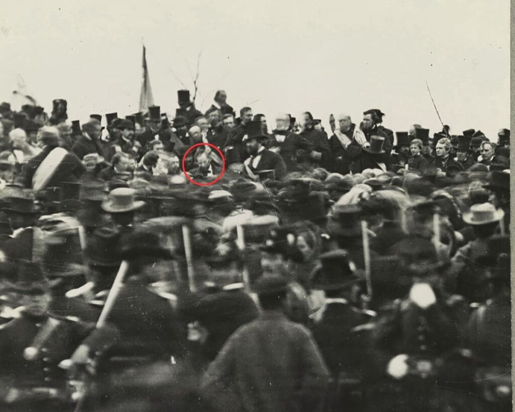 Historic black-and-white photograph showing the crowd gathered at Soldiers’ National Cemetery in Gettysburg on November 19, 1863, during the dedication ceremony where President Abraham Lincoln delivered the Gettysburg Address, with Lincoln circled at the center of the image.