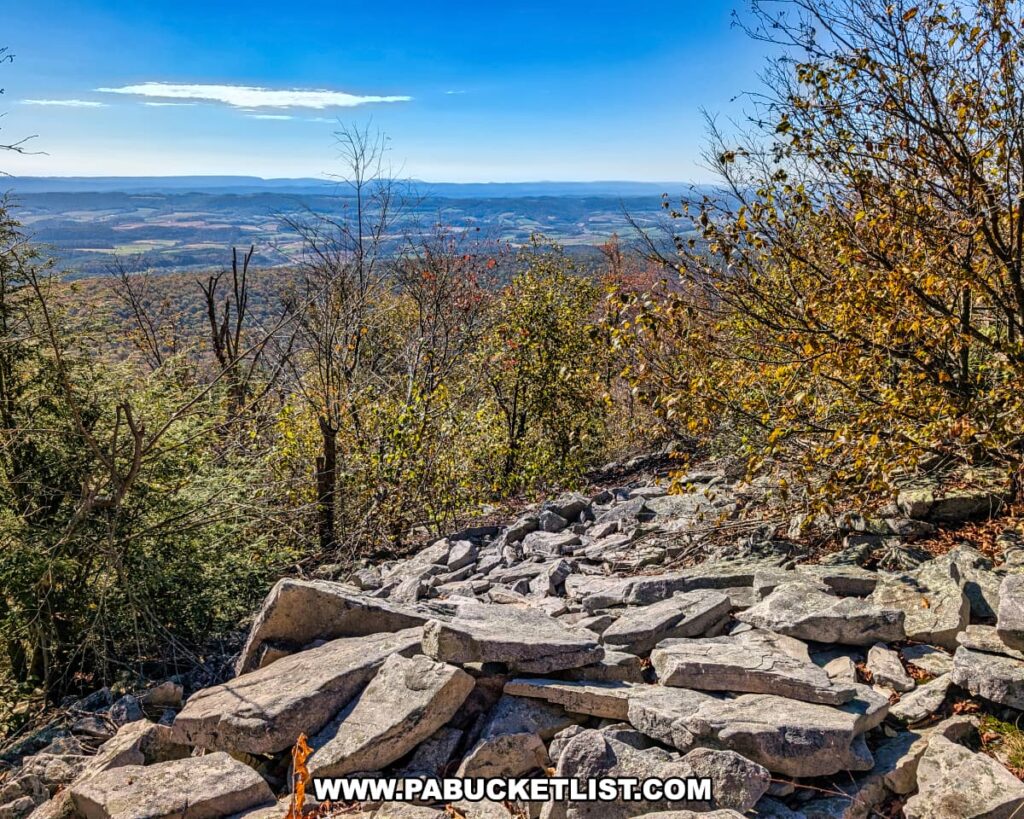 Rocky overlook along the Mid State Trail near Harry’s Valley Vista in Rothrock State Forest, offering a sweeping view of rolling ridges and valleys framed by autumn foliage under a clear blue sky.