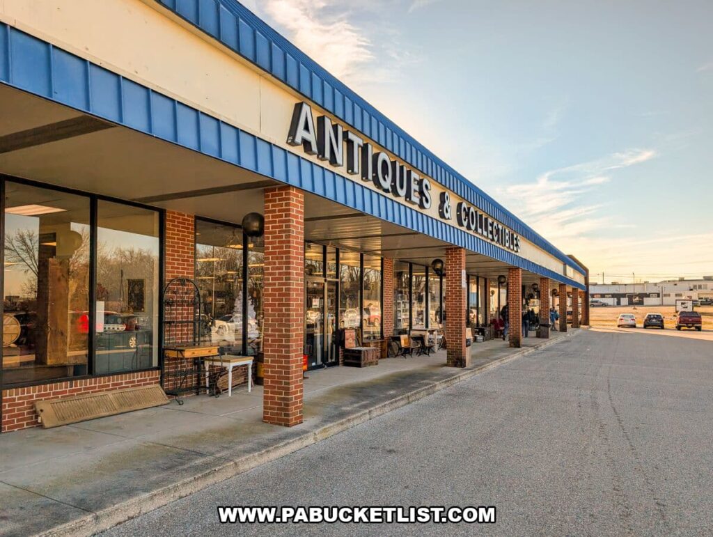 Exterior view of Black Rose Antique & Collectibles at North Hanover Center in Hanover, Pennsylvania, featuring a long brick storefront with large display windows, outdoor antique items, and a parking lot under a clear sky.