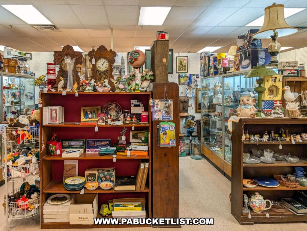 Vintage-themed vendor booth inside Black Rose Antiques in Hanover, Pennsylvania, showcasing shelves of collectibles including wooden clocks, figurines, toys, dishware, lamps, and boxed items, with glass display cases and other booths in the background.