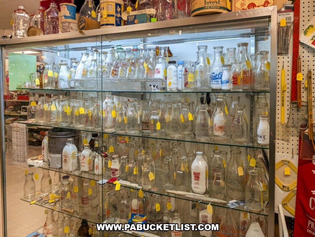 Glass display case filled with vintage milk bottles at Black Rose Antiques in Hanover, Pennsylvania, showcasing rows of embossed and labeled bottles from various dairies alongside related antique dairy collectibles.