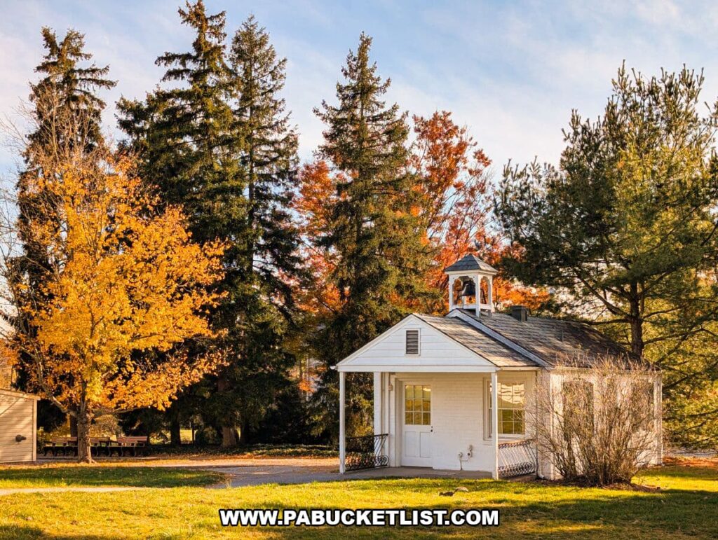 Small white guest house with a cupola at the Eisenhower National Historic Site, surrounded by tall evergreens and vibrant fall foliage under a clear blue sky.