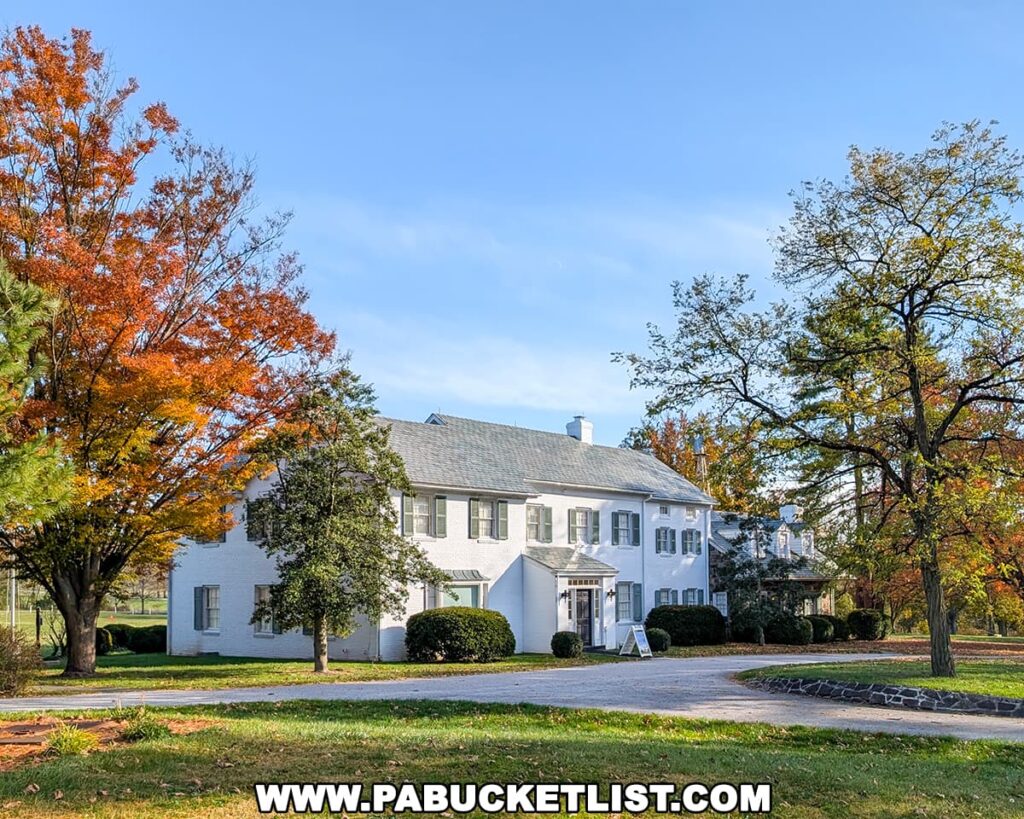 White two-story Eisenhower farmhouse framed by colorful fall foliage, sitting along a circular driveway at Eisenhower National Historic Site in Gettysburg.